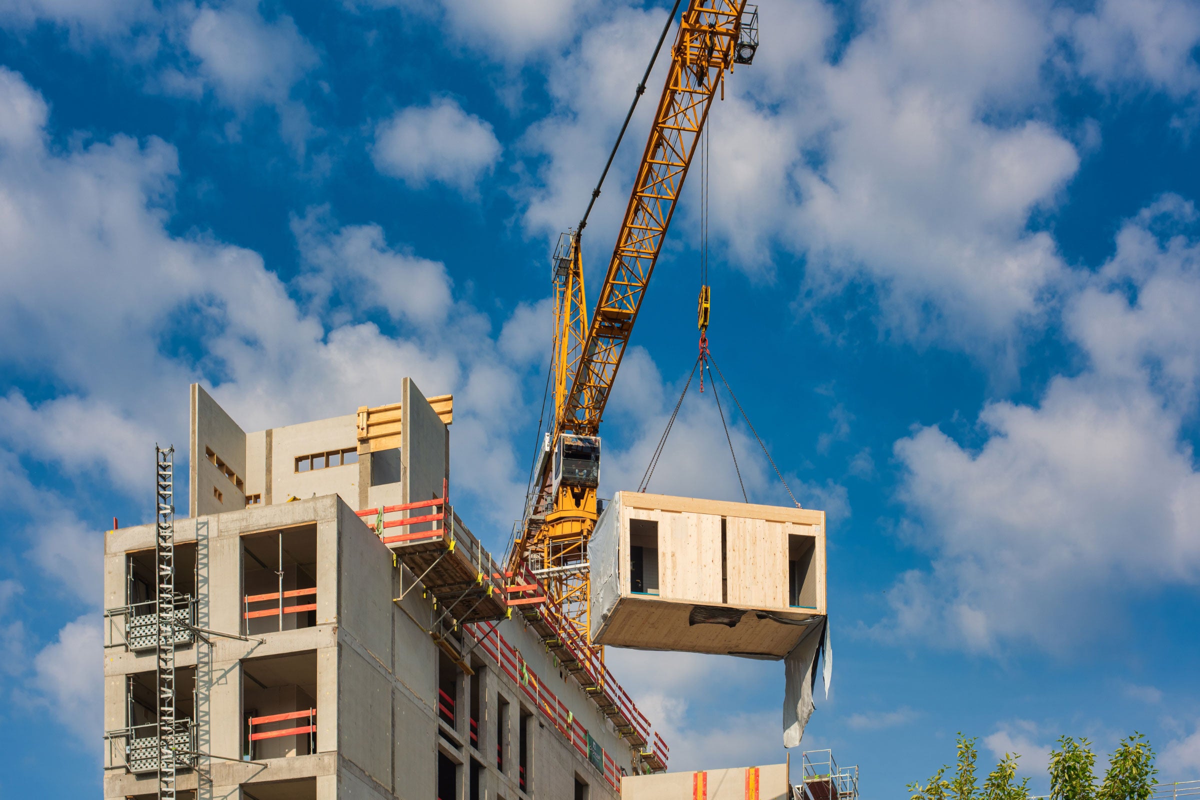 Crane lifting a prefabricated wooden building module to its position in the structure