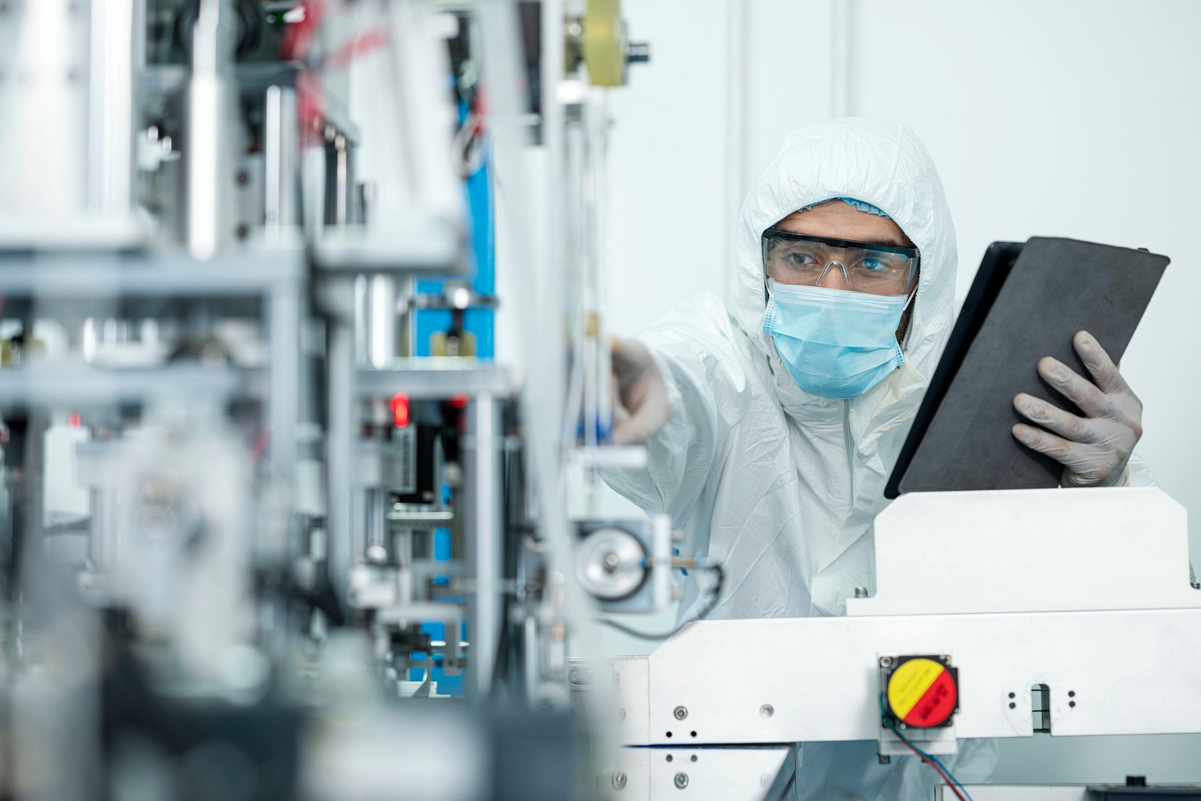 Shot of Caucasian Engineers using digital tablet for inspection quality of producing protective face mask in automated production line.