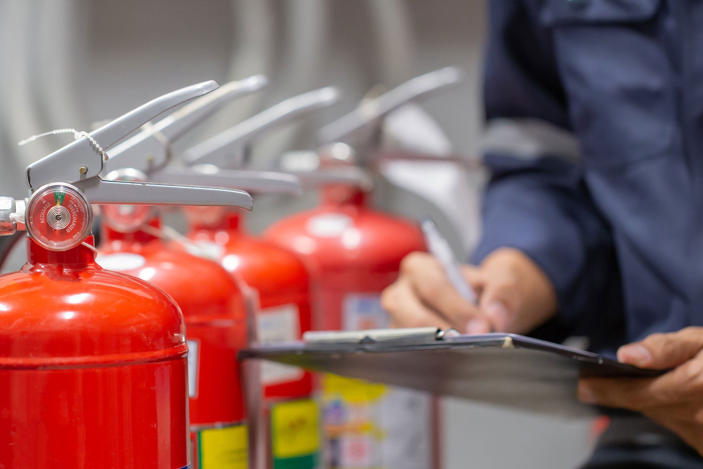 Engineer inspecting a row of fire extinguishers in the fire control room for safety training and fire prevention.