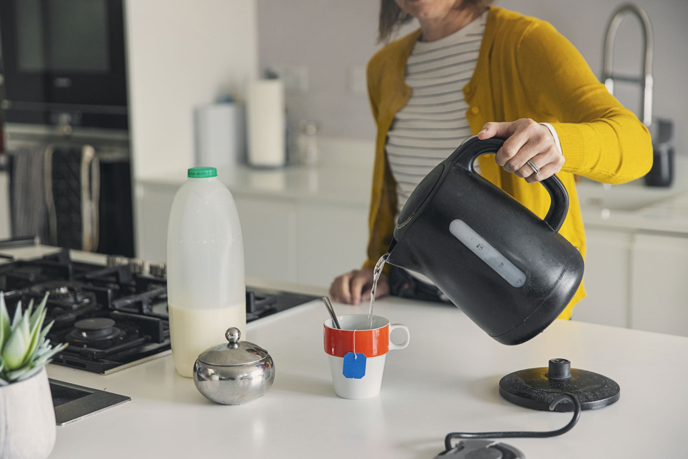 a person pouring hot water from an electric kettle