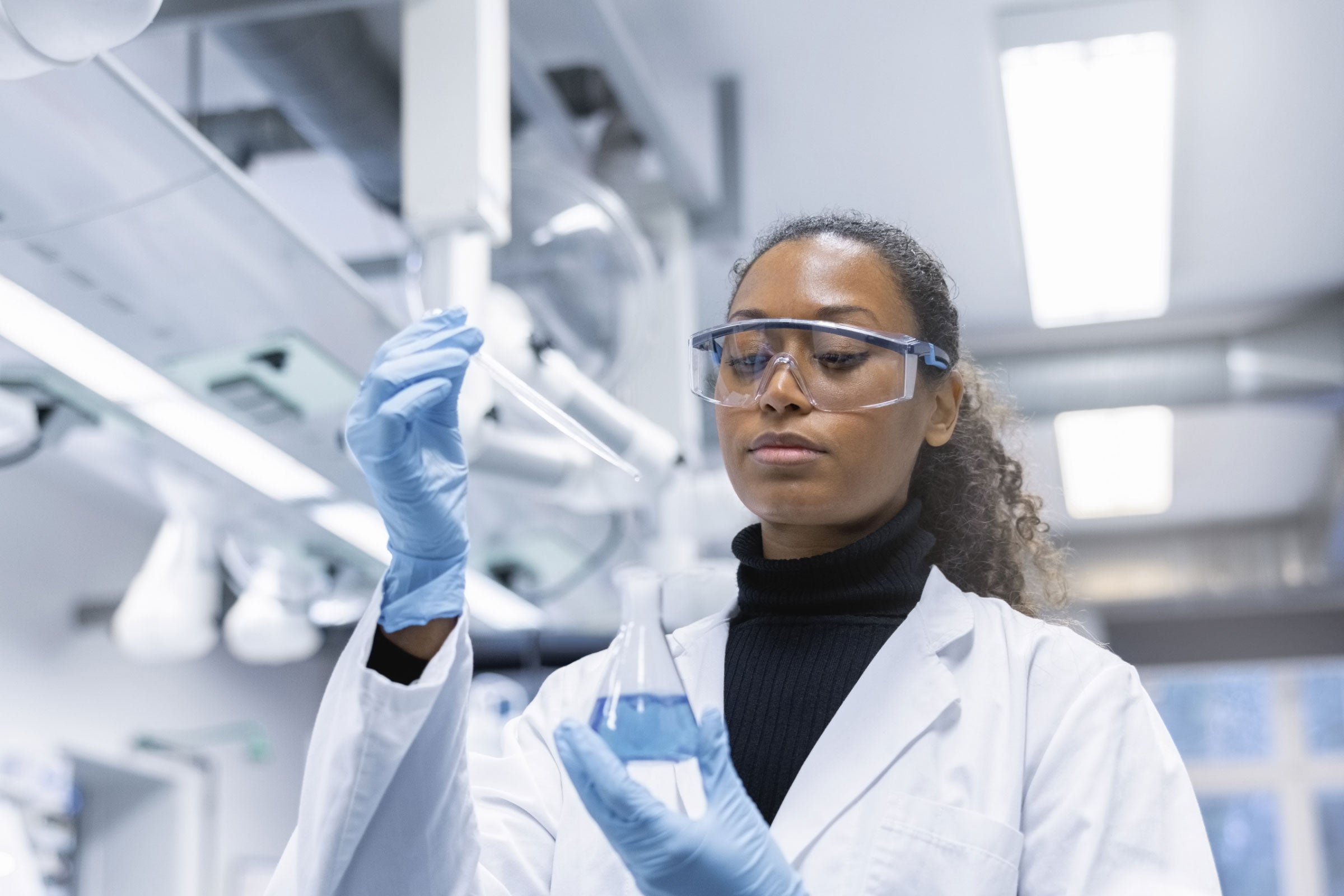 A person using a dropper and a beaker