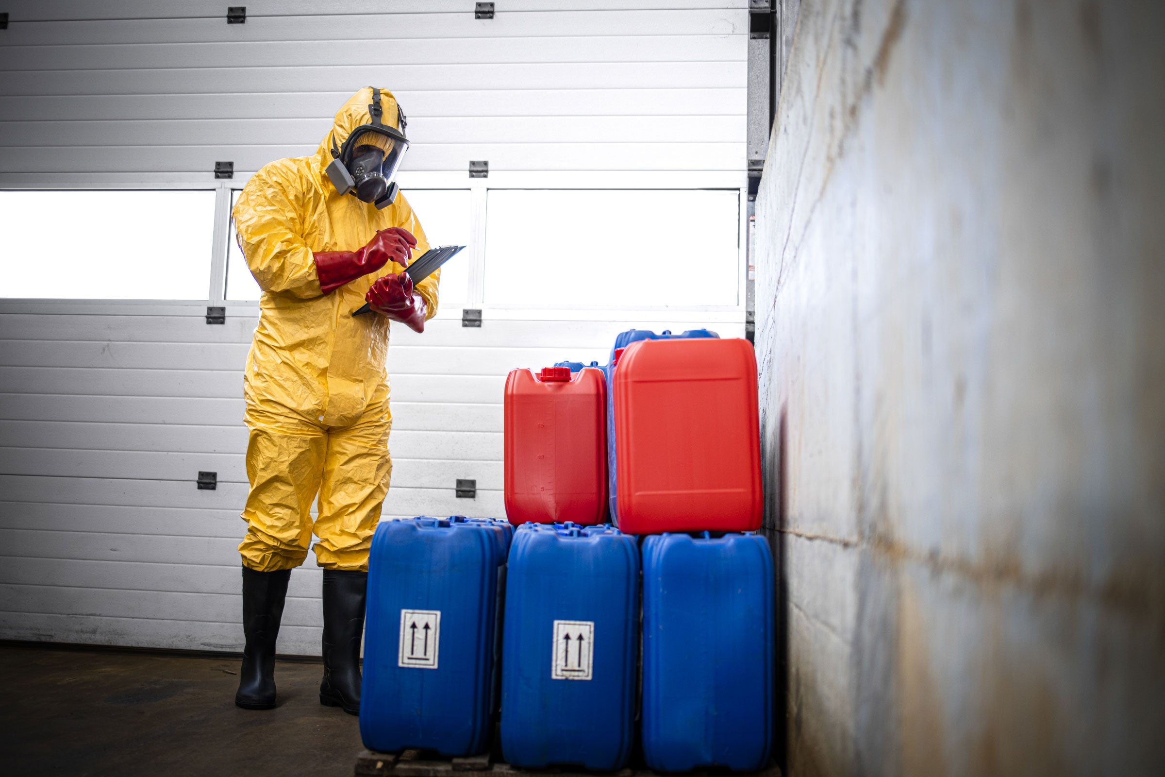 a person wearing PPE checking chemical containers