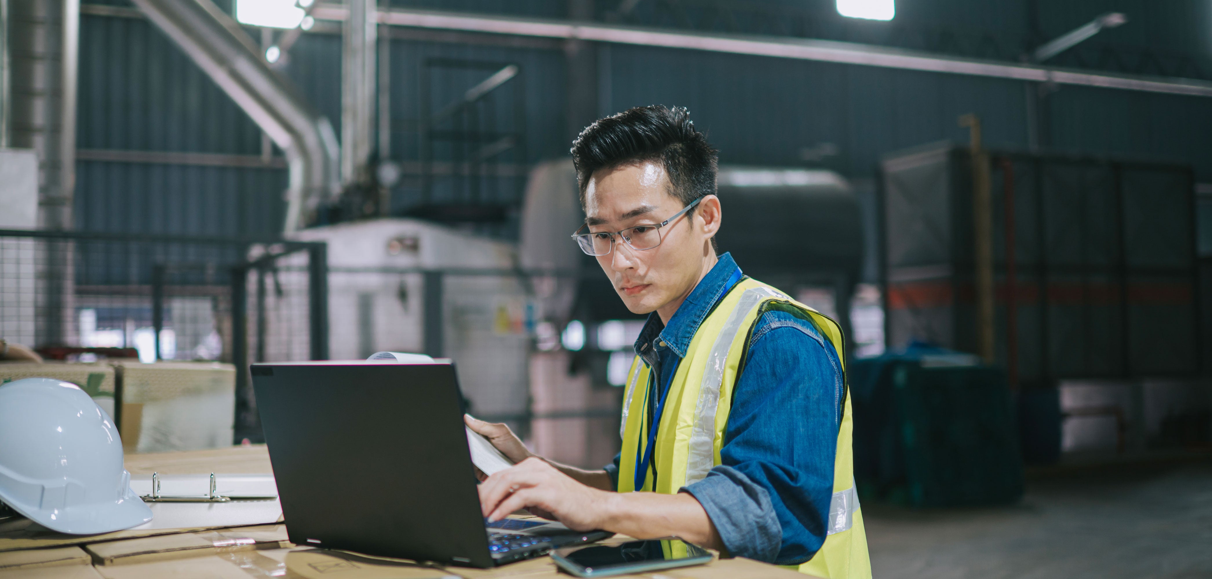 Warehouse manager using a laptop inside a warehouse