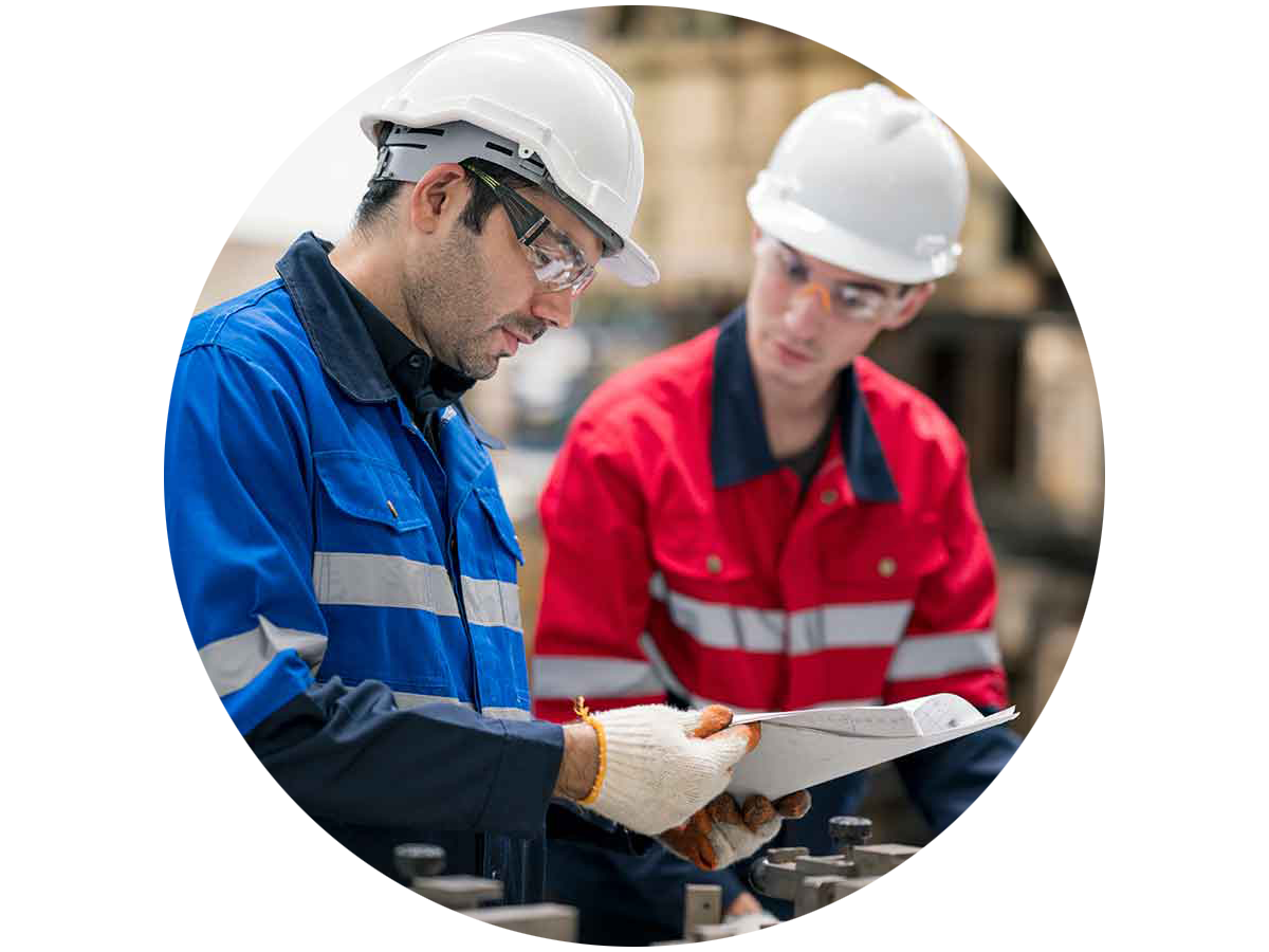 Two engineers looking over papers on a clipboard in a factory setting