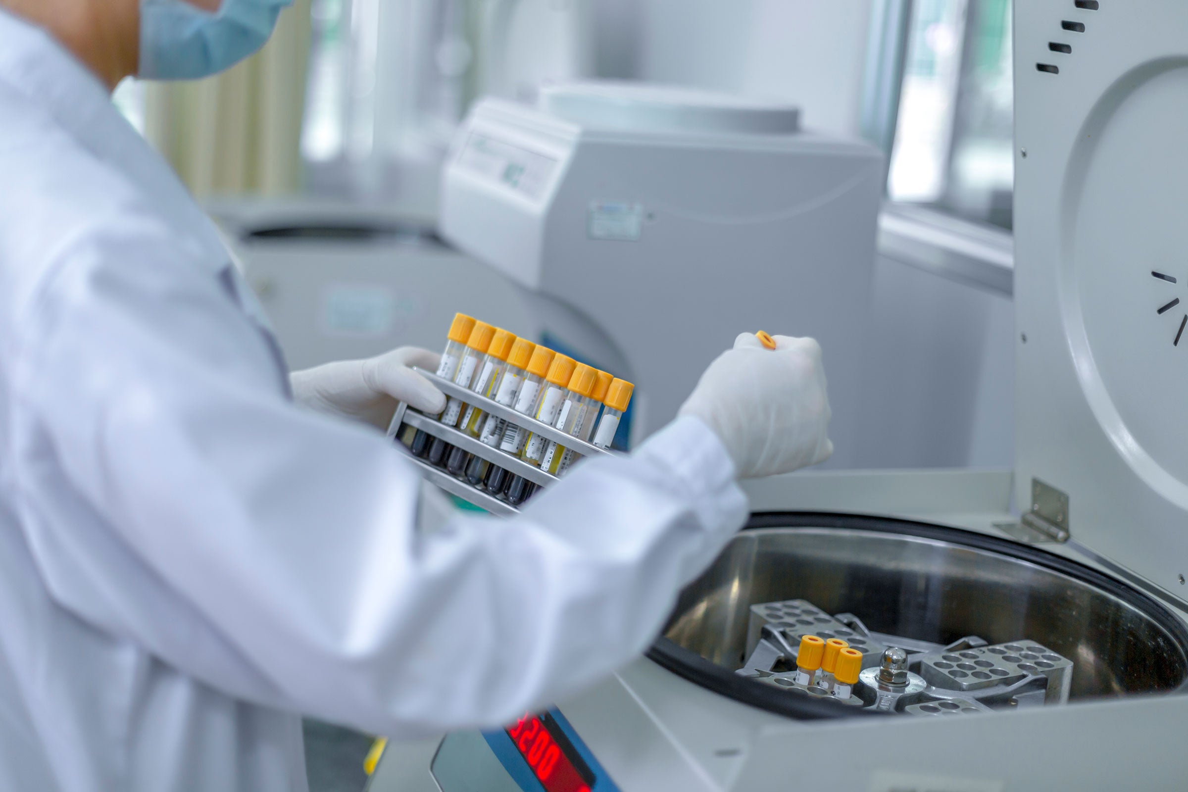 A lab technician placing samples into a centrifuge 