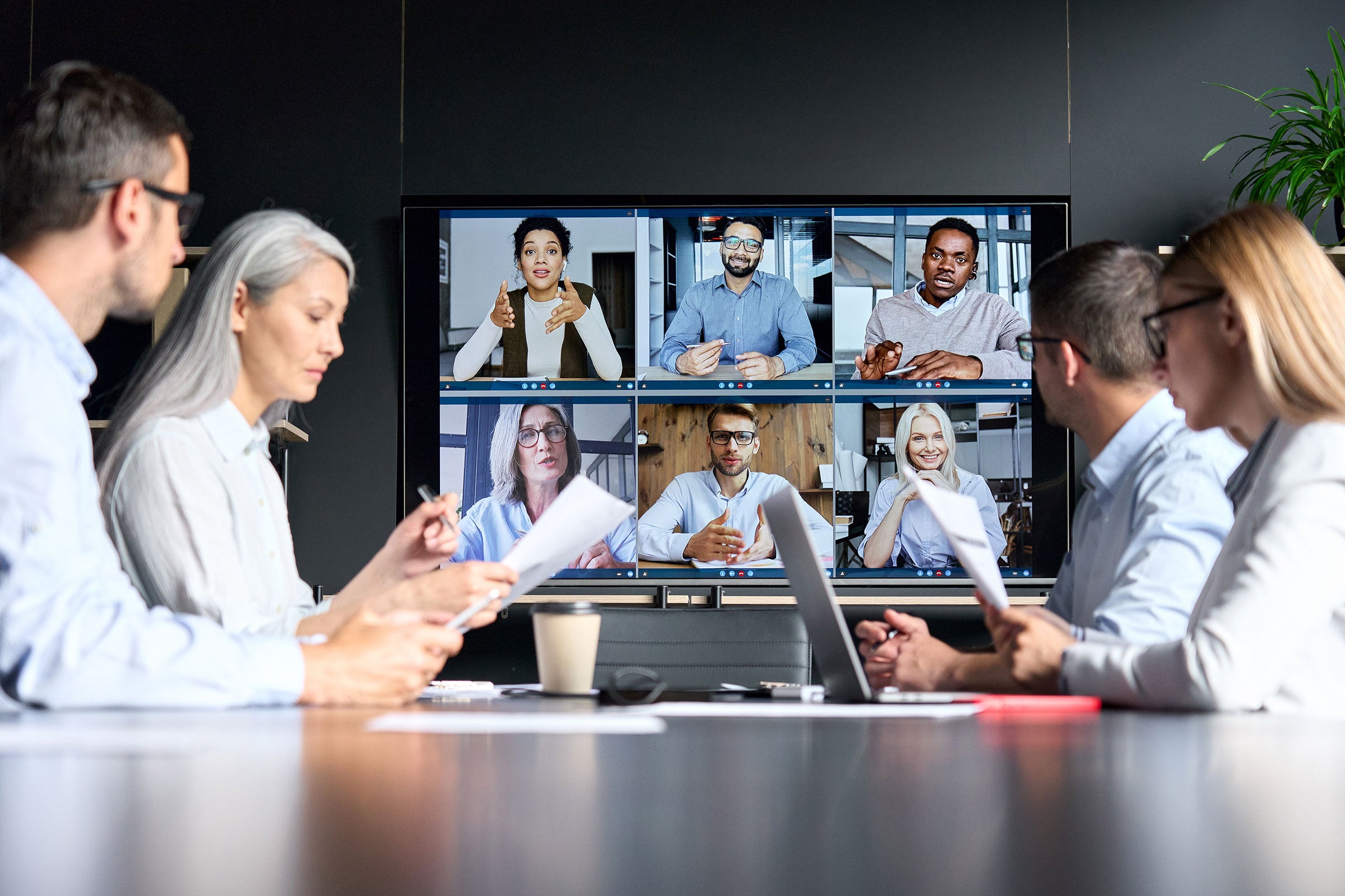 Medical professionals sitting at a conference table while having a virtual meeting