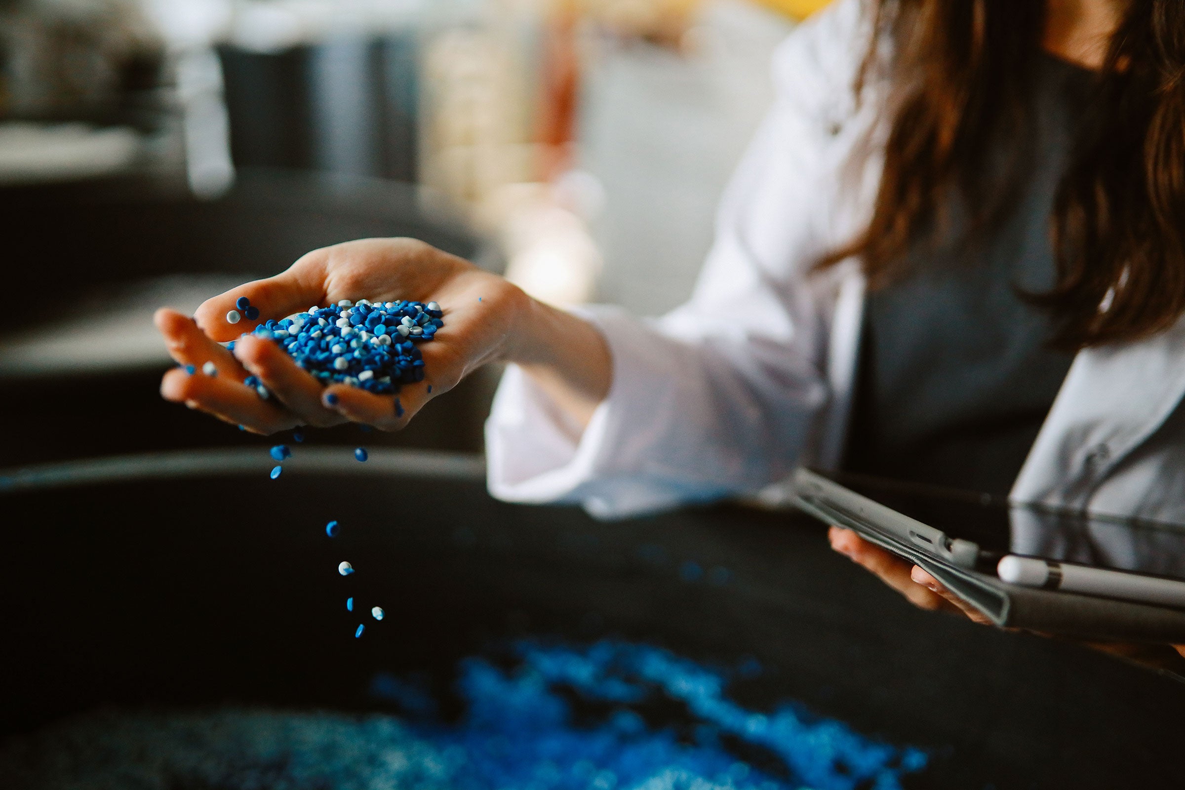 Chemist holding a handful of blue plastic pellets