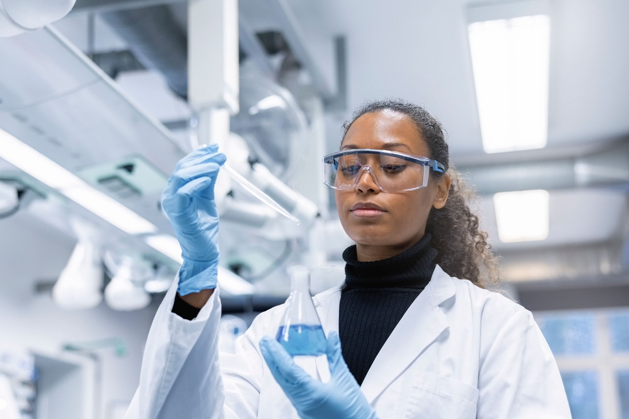 Chemist adding a sample to a solution in conical flask