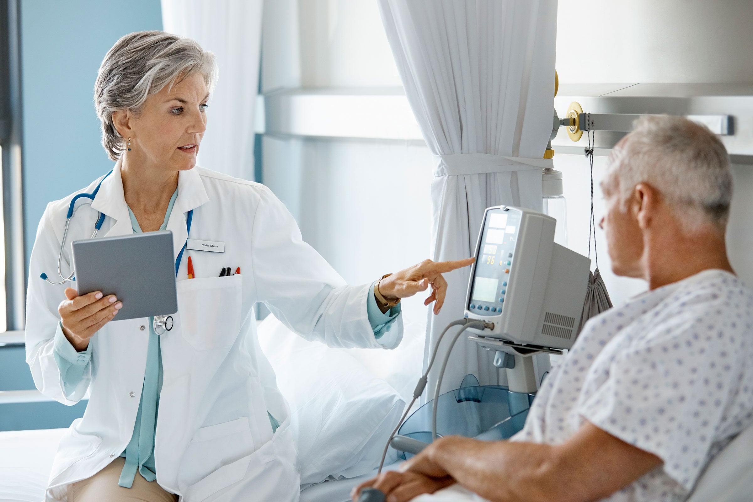 A doctor checking the vital stats of a patient laying in a hospital bed