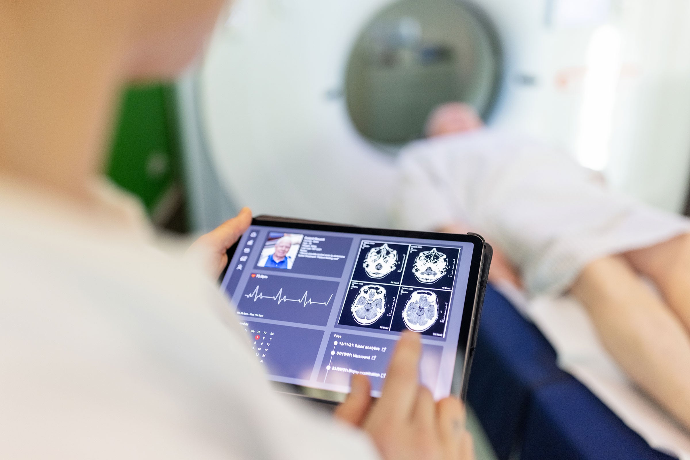 Neurologist examining patient's CAT scan images on digital table in a clinic