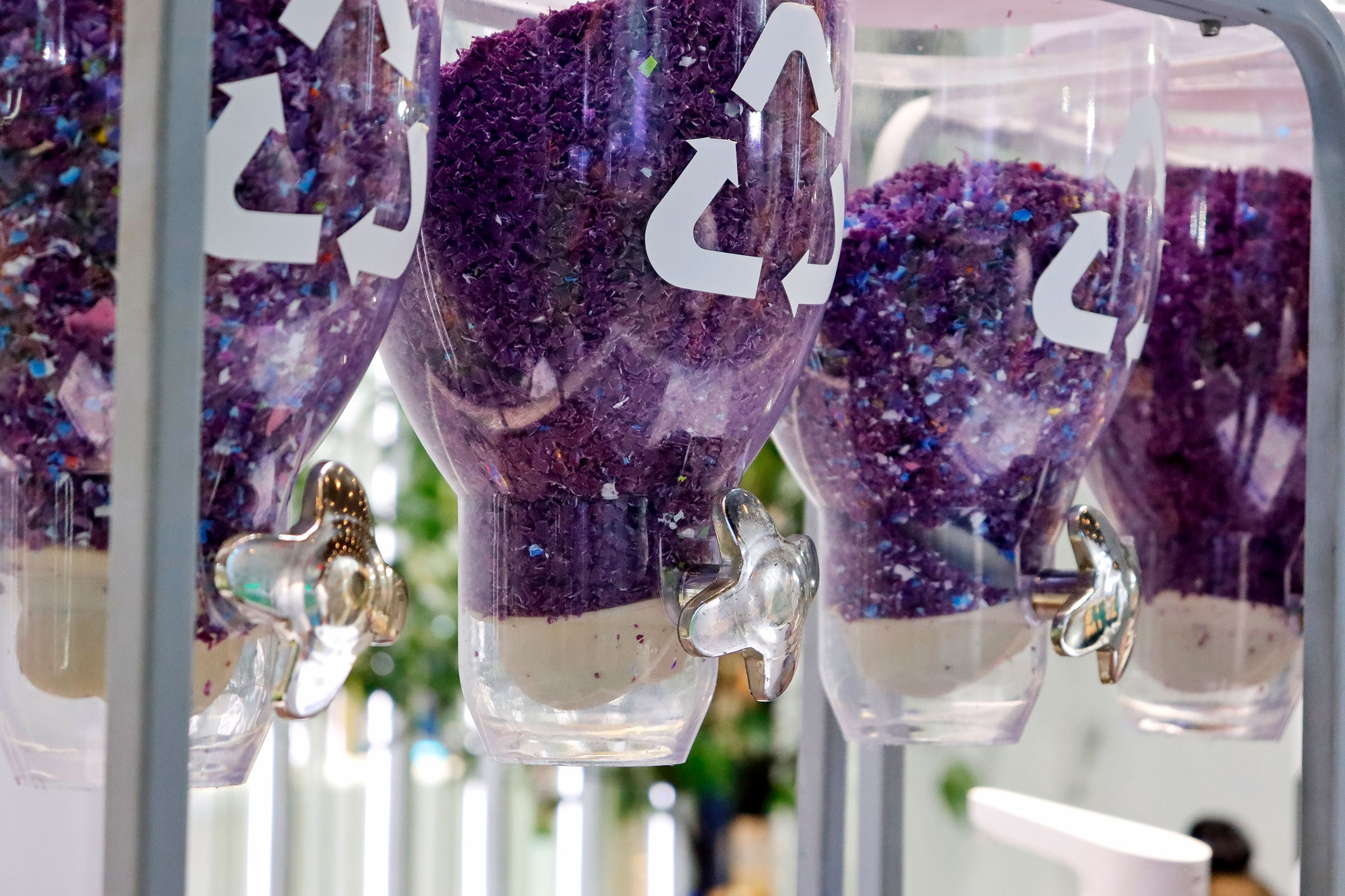 Hanging dispensers containing bright purple shredded recycled plastic