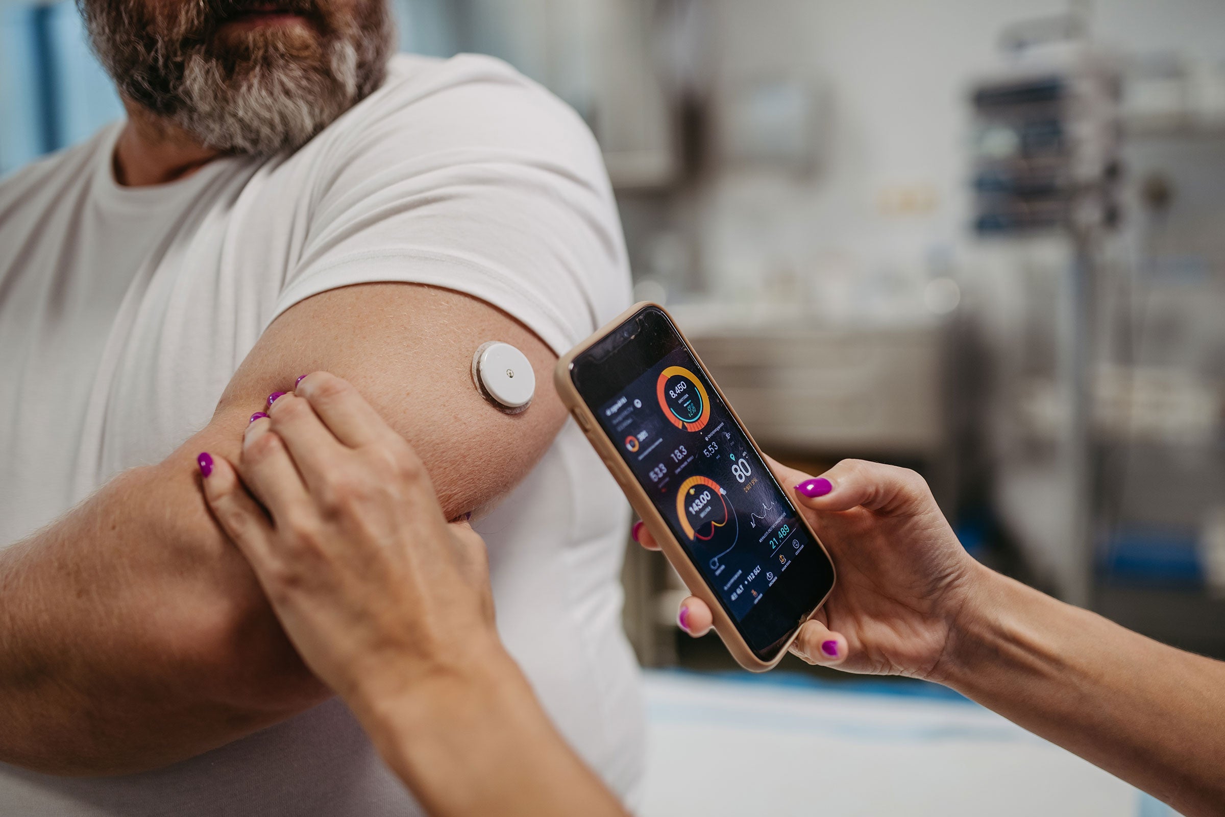 Close up a nurse using a mobile device to scan a patient's CGM