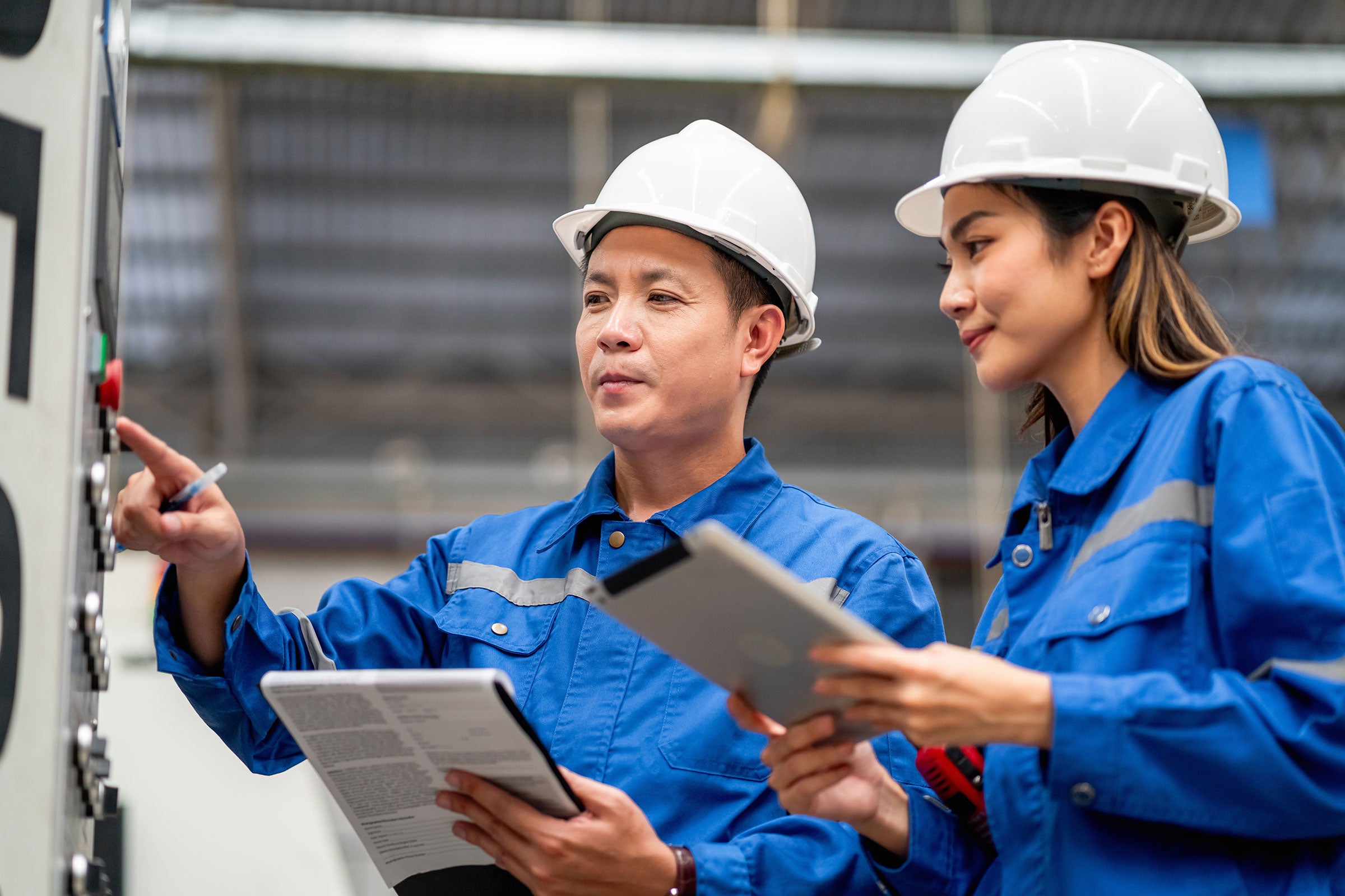 Maintenance engineer inspects machinery in a cardboard parts factory