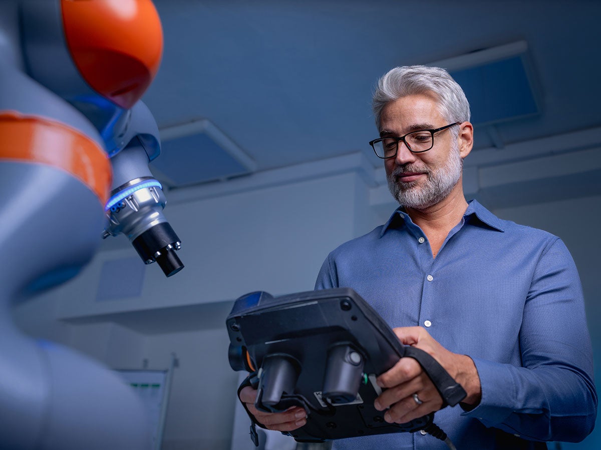 Robotics engineer holding a remote control while working on robotic knee replacement surgery project