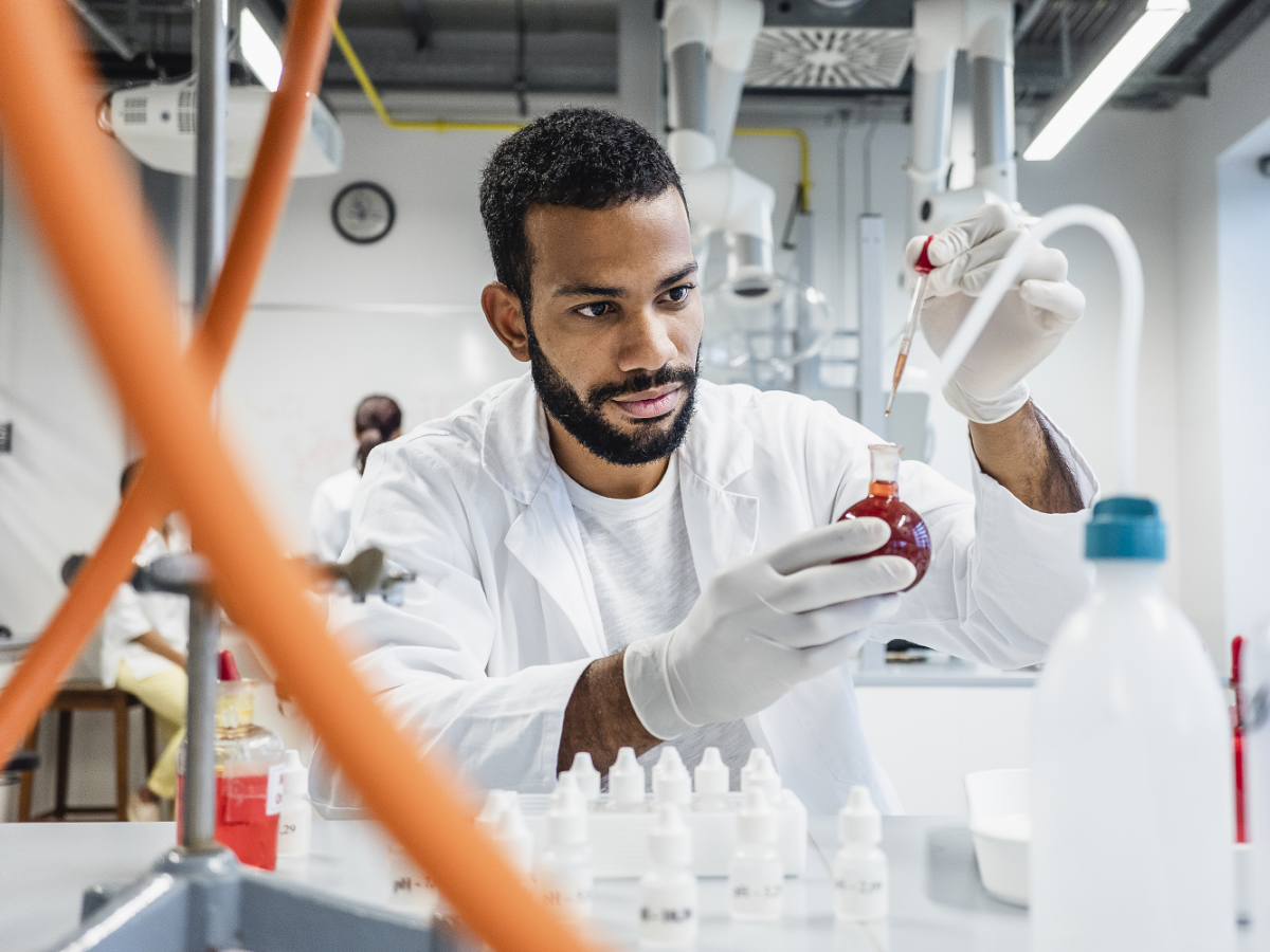 scientist dropping a chemical into round bottom flask