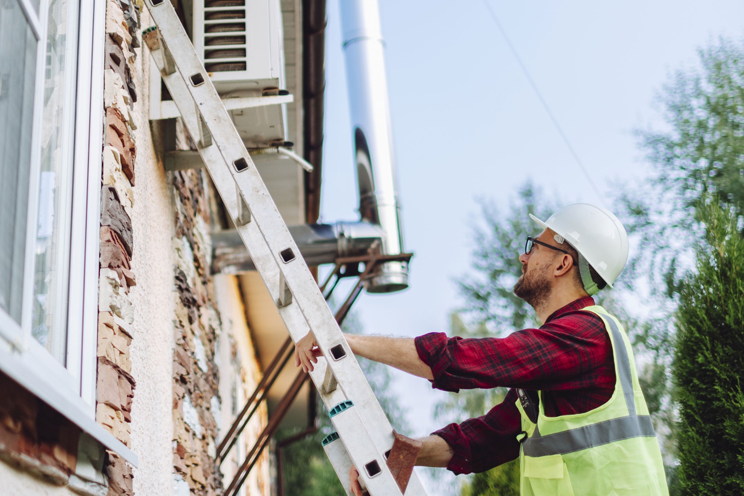 A worker climbing a ladder and wearing PPE