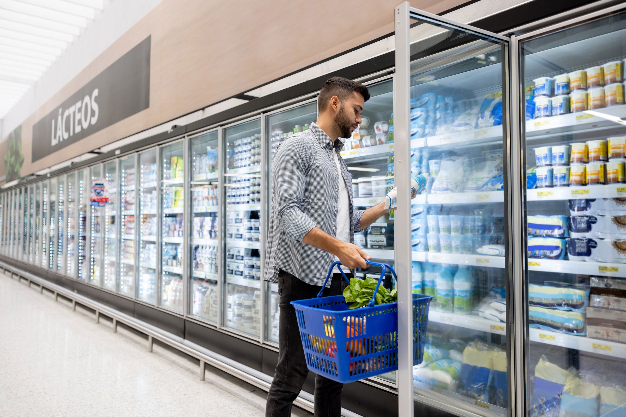 a person opening a refrigeration door in a grocery store