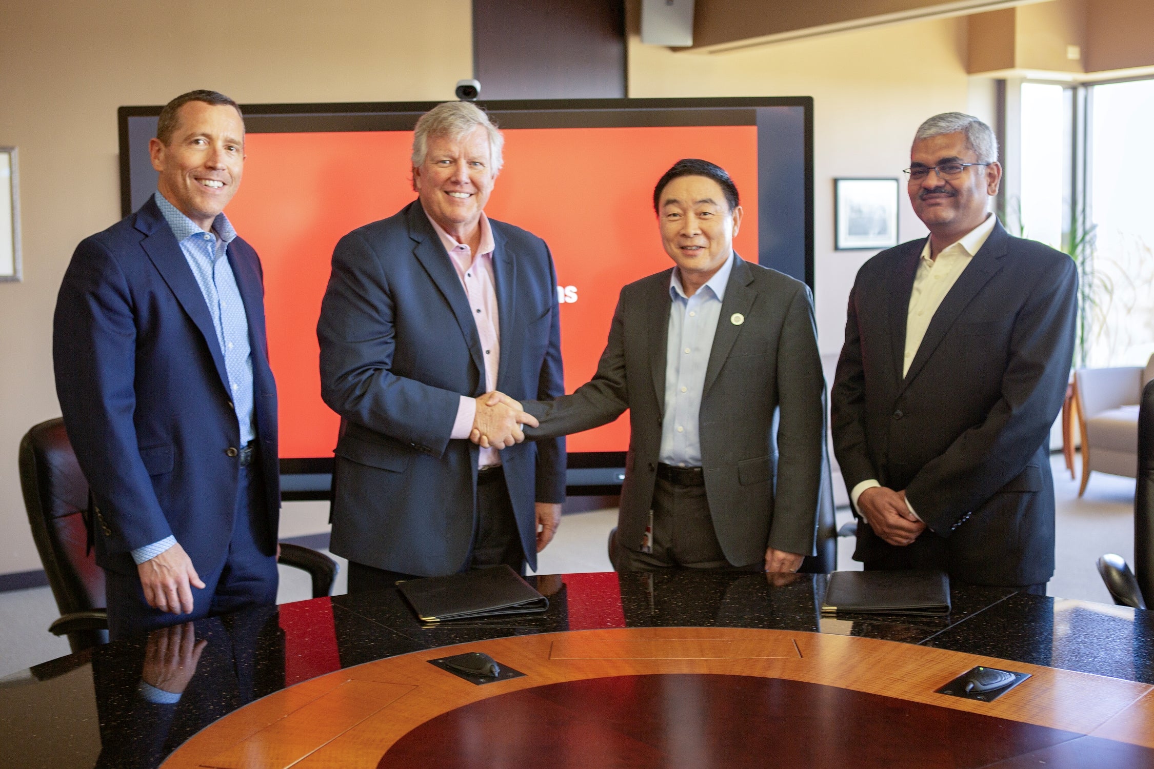 At a ceremony at UL Solutions headquarters in Northbrook, Illinois, Dave Hopping, global CEO of smart infrastructure solutions and services at Siemens, and Weifang Zhou, executive vice president and president of Testing, Inspection and Certification at UL Solutions, shake hands after signing an agreement to collaborate on smart building assessments through the SPIRE qualification program.