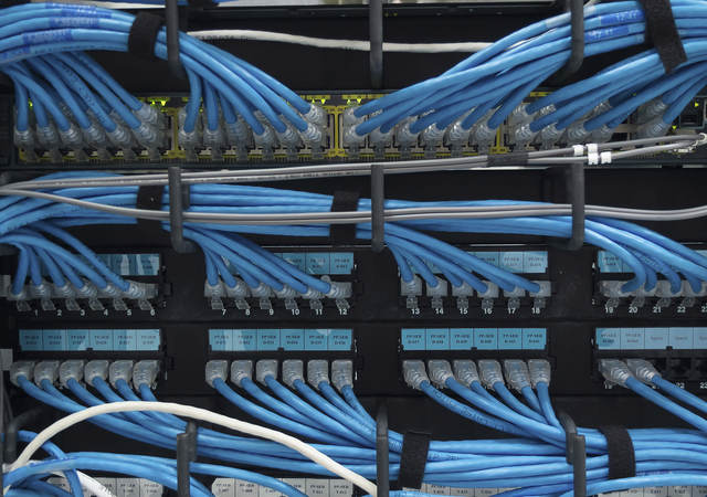 A close-up image of blue ethernet cable plugged into a data center. 