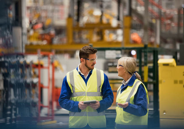 Workers collaborating in a warehouse with a tablet