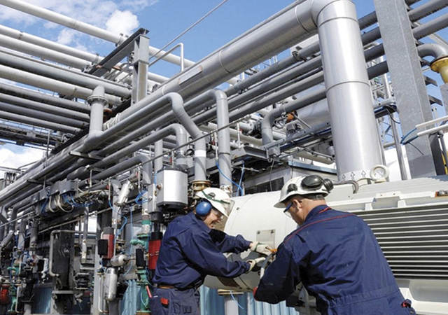 Two workers at refinery working next to pipes