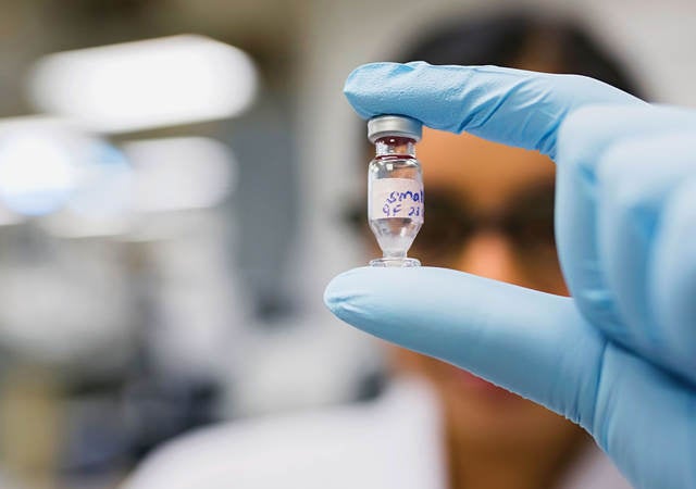 Gloved hand holding a chemical vial in a laboratory setting