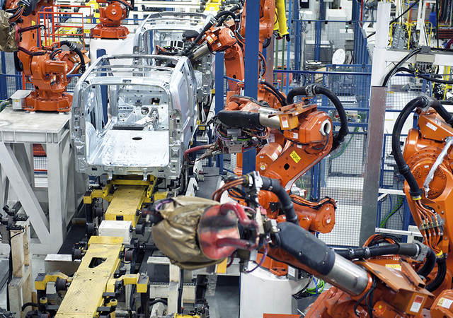 Vehicle factory manufacturing with robotic arms and automation.