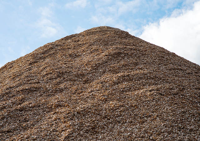 Pile of mulch woodchips against a blue sky