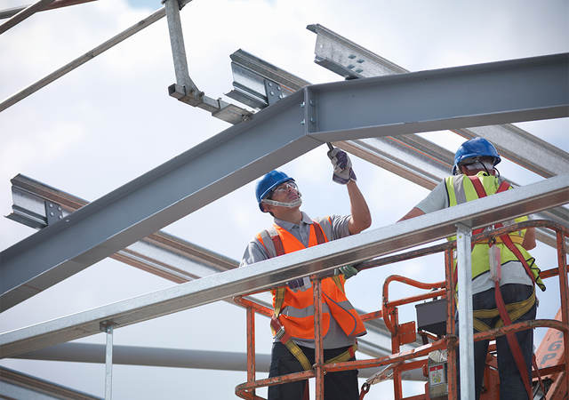 A construction worker laboring on a steel structure