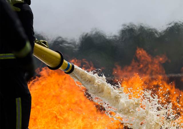 Firefighter spraying a fire with foam hose