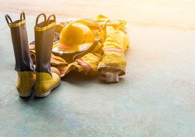 A yellow fireman’s uniform and boots laying on the ground. 