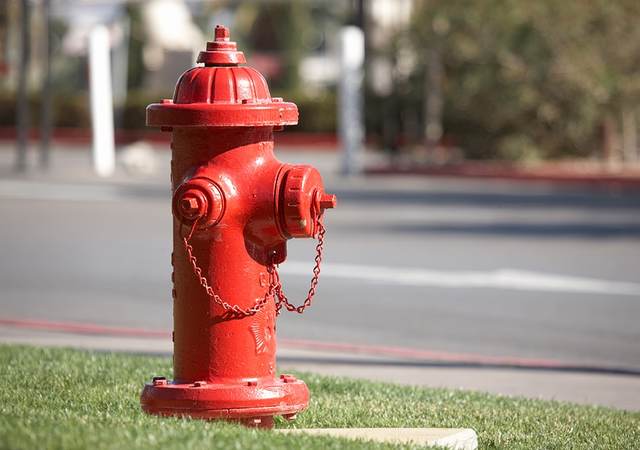 A bright red fire hydrant along a road.