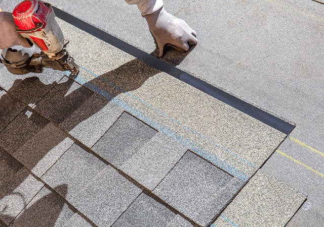 A worker nailing shingles on to a new roof. 