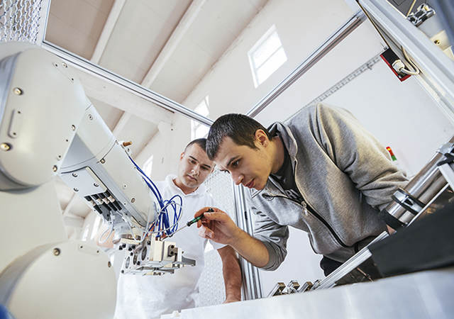 Two men work on robot.