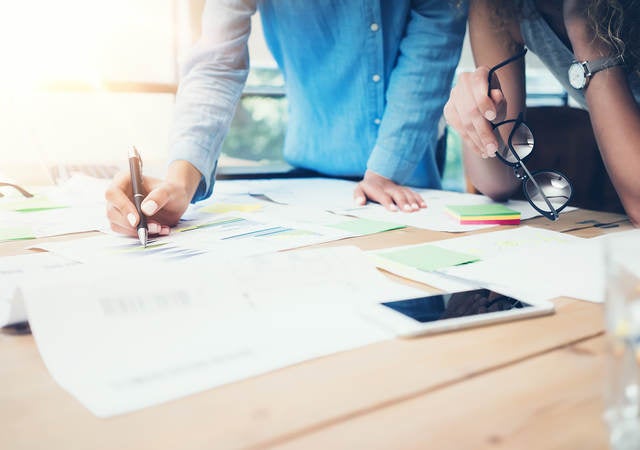 A man and a woman make notes on charts and graphs.