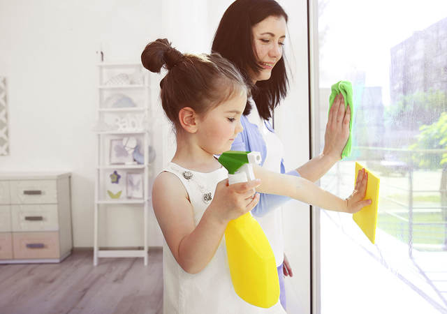 Girl helping her mother clean windows