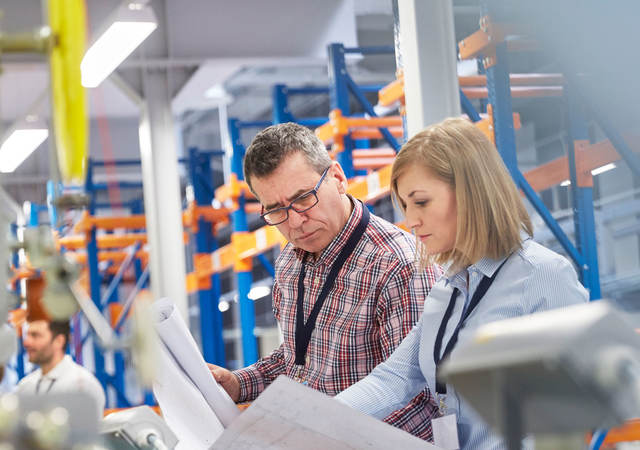 Two people at work looking at printed plans