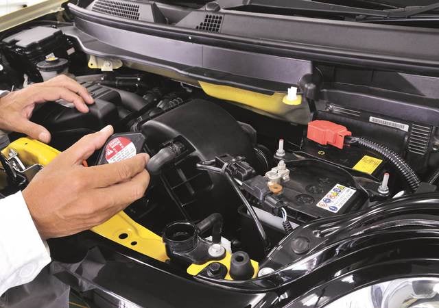 Inside hood of a car focusing on a part with a label