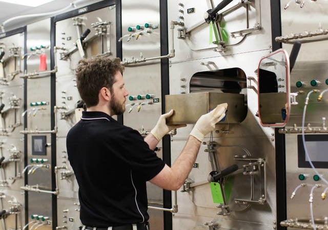 Man using a bank of small testing chambers to determine VOC emissions from products.