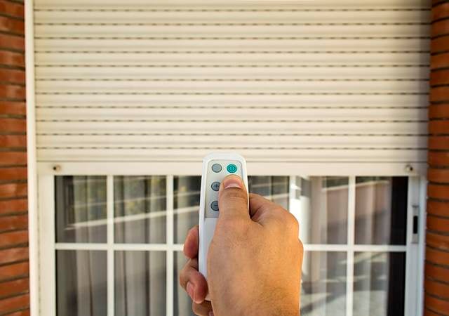 hand holding remote in front of a window