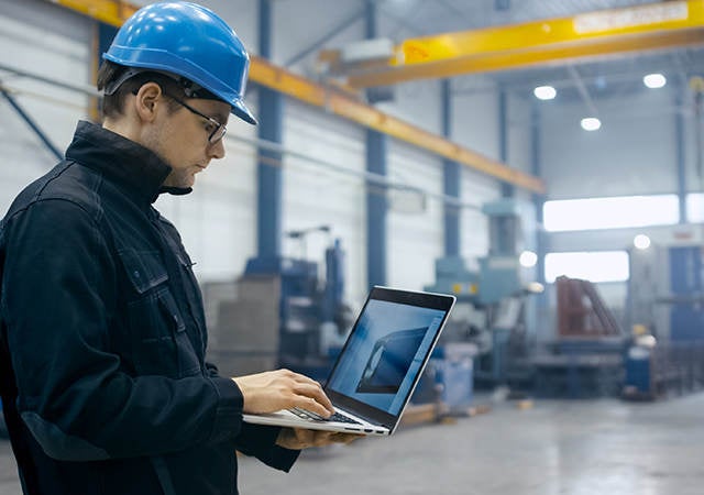 Worker in a hardhat using a laptop