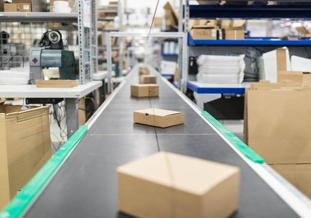 Cardboard boxes on conveyor belt at distribution warehouse