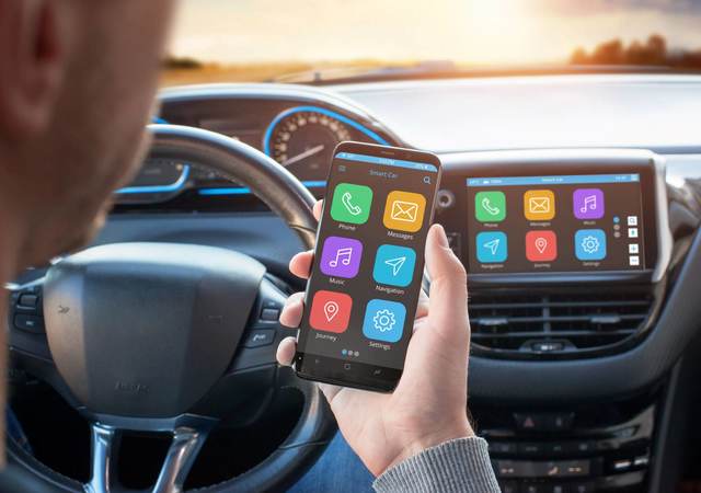 Driver uses a mobile phone with smart driving assistance apps. The app is connected to a car computer and is displayed on the board display.