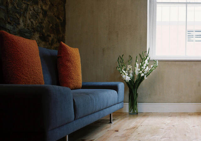 Photo of a blue couch with orange throw pillows