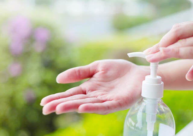 Female hand dispensing hand sanitizer onto open palm