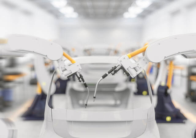 Car being built on assembly line in factory with robot arm adding parts to car