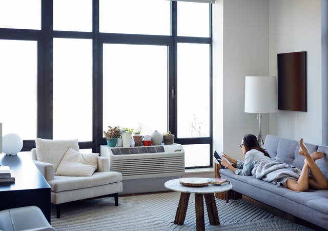 Woman reading book while lying on sofa at home