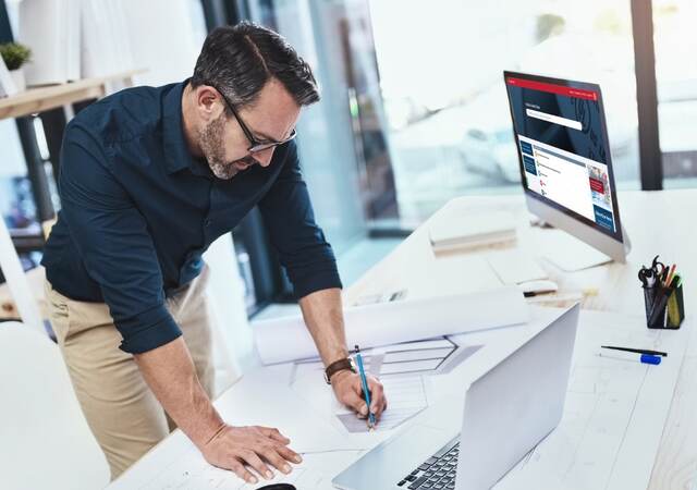 Man at desk looking at computer with Product iQ on screen. 