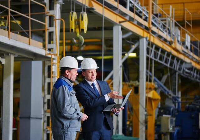 Two men in warehouse looking at laptop