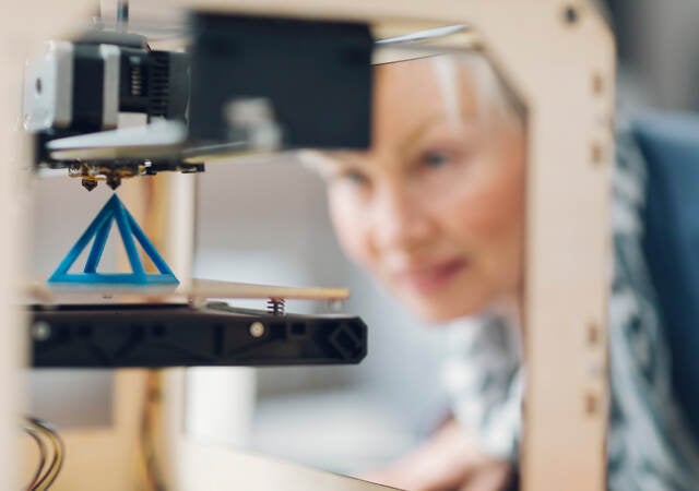 Photo of a woman working by a 3D printer